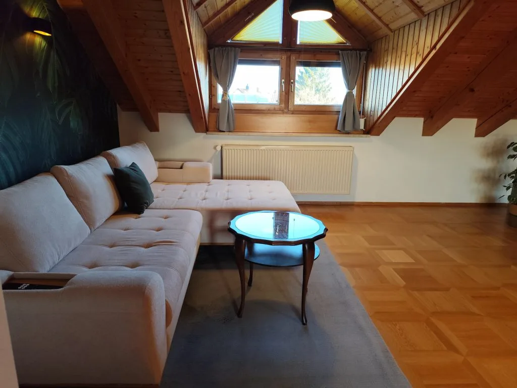 Wohnzimmer der Ferienwohnung Burgzauber im Haus 113 in Burghausen mit Sofa und Dachschräge