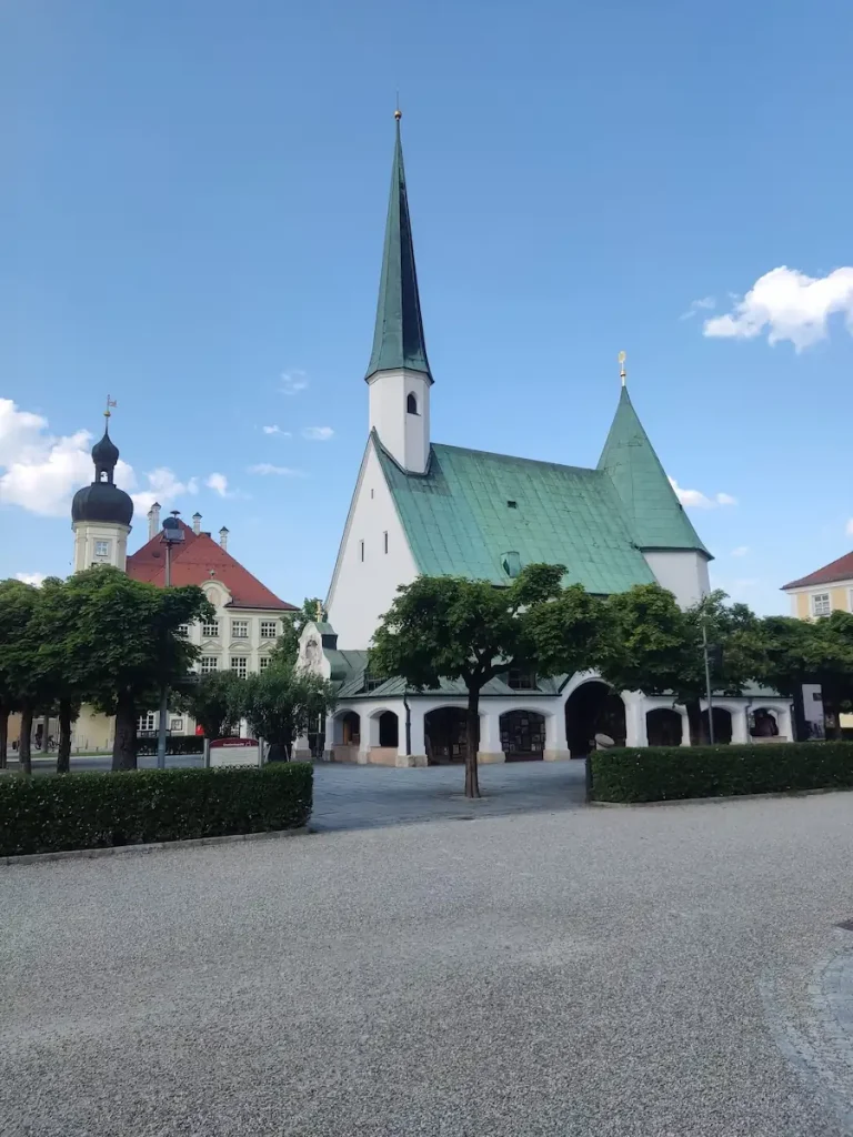 Kirche mit zwei Zwiebeltürmen an einem gepflasterten Platz in der Region Burghausen