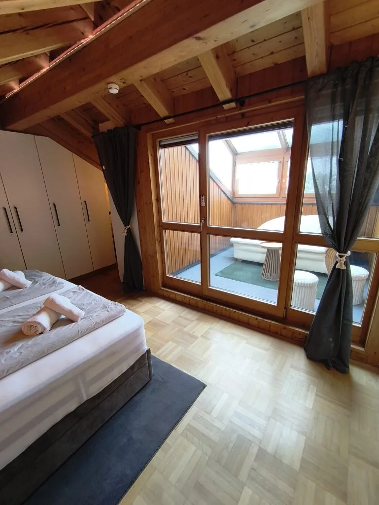 Schlafzimmer der Ferienwohnung Burgzauber mit Doppelbett unter der Dachschräge und großem Fenster