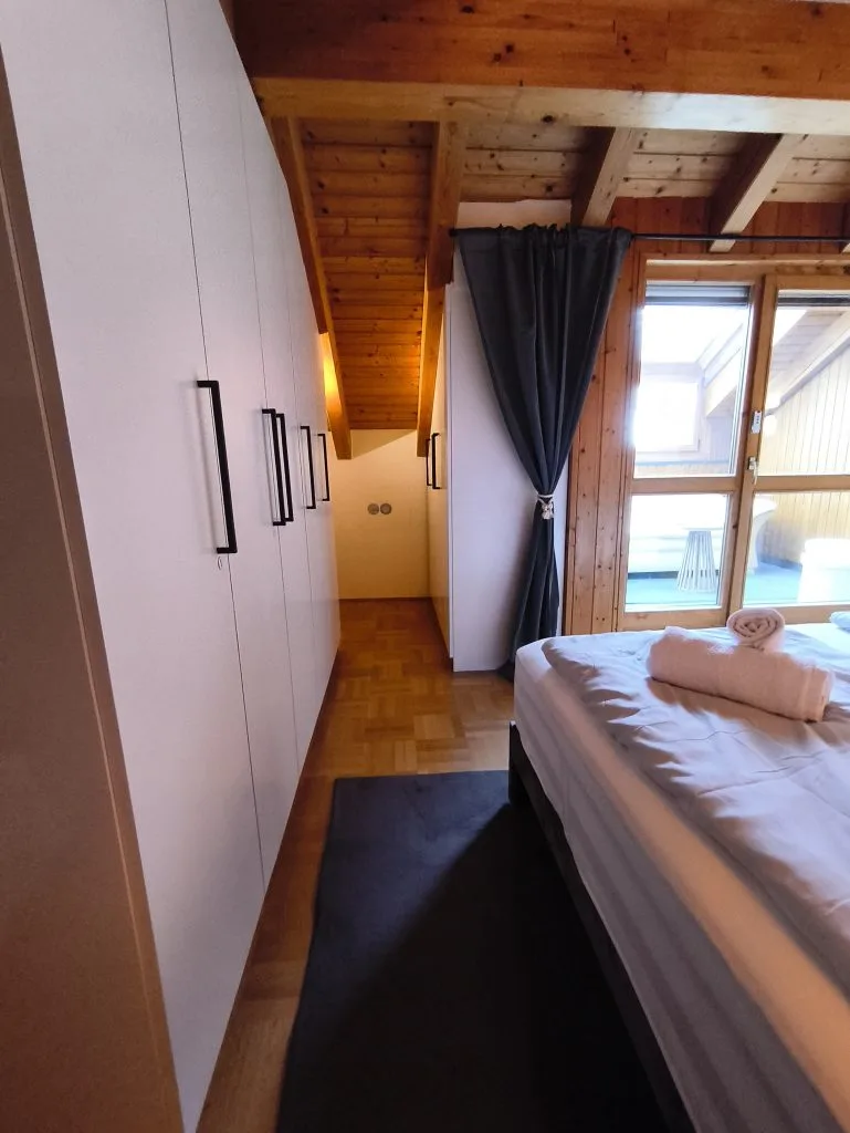 Schlafzimmer der Ferienwohnung Burgzauber mit Kleiderschrank und Doppelbett unter Holzdachschräge