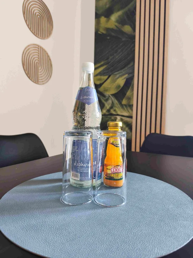 Runder Tisch mit Wasserflasche und Getränk als Willkommensgruß in der Ferienwohnung Burgperle