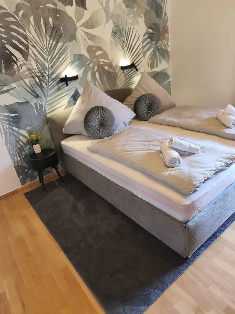 Doppelbett der Ferienwohnung Burgperle mit Handtuchdekoration vor tropischer Fototapete