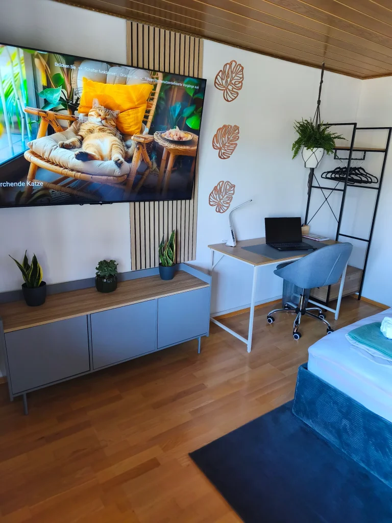 Wohnbereich der Ferienwohnung Burgperle mit Fernseher, Regal und Schreibtisch