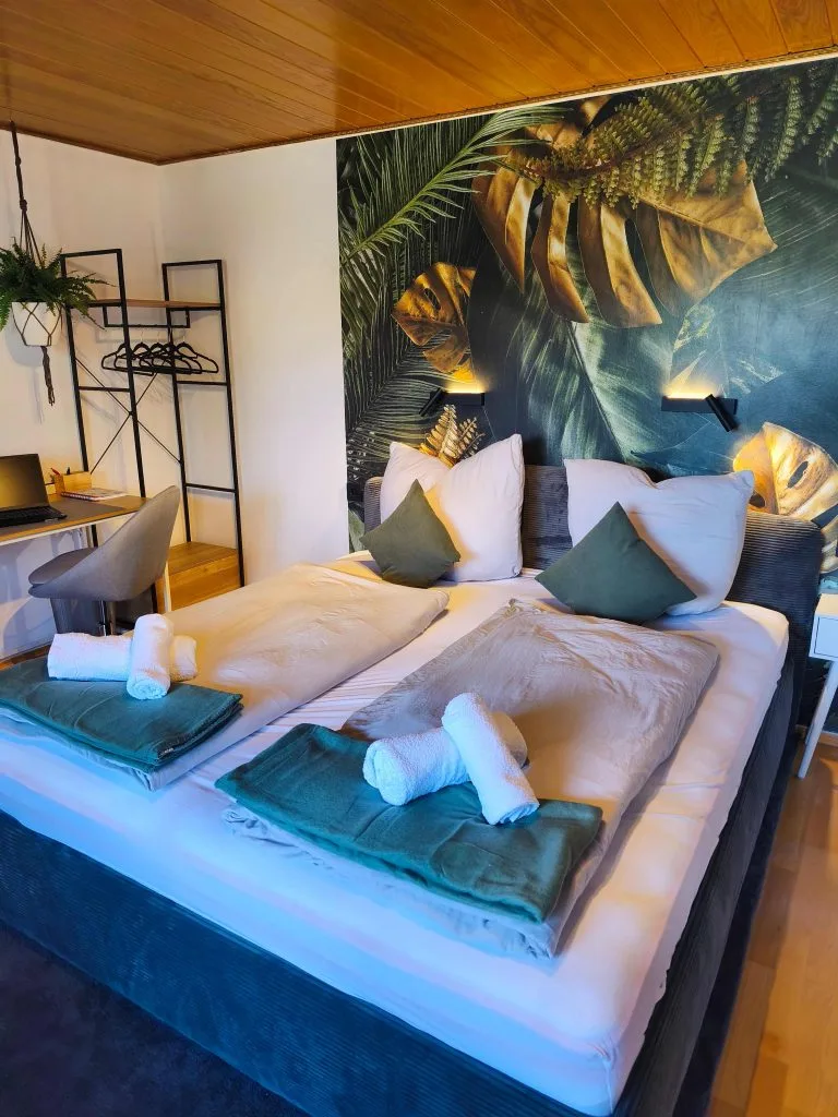 Schlafzimmer der Ferienwohnung Burgperle mit Doppelbett vor tropischer Fototapete