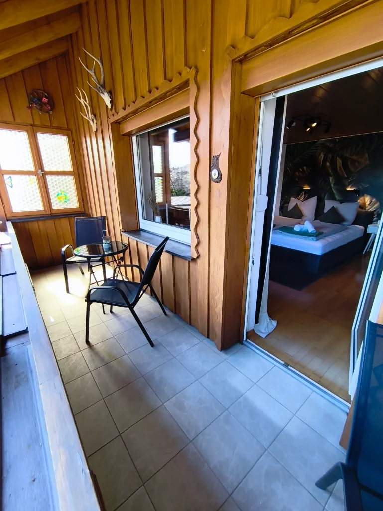 Sonniger Holzbalkon der Ferienwohnung Burgperle im Haus 113 in Burghausen mit Tisch und Stühlen