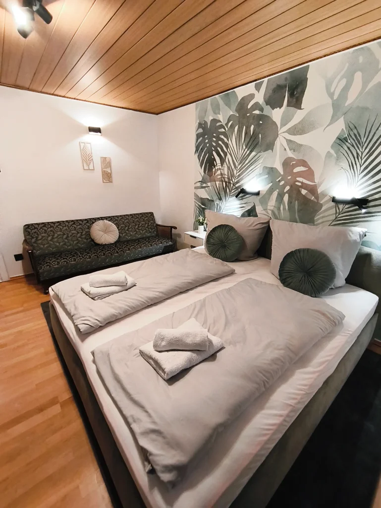 Schlafbereich der Ferienwohnung Burgperle mit Doppelbett unter Holzdecke