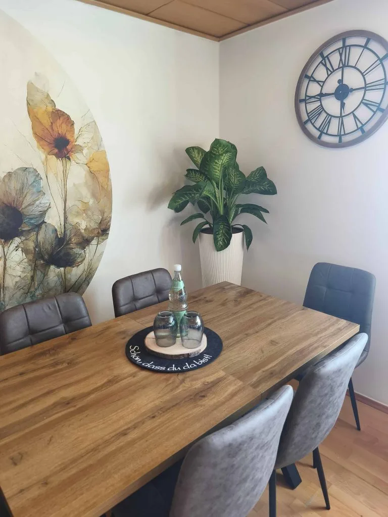 Essbereich der Ferienwohnung Burgjuwel mit Holztisch, gepolsterten Stühlen und floralem Wandbild