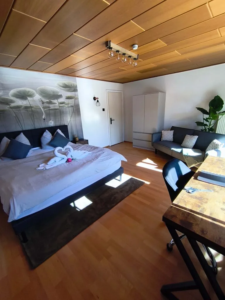Schlafbereich der Ferienwohnung Burgjuwel mit Doppelbett unter Holzschräge und Blick zum Essbereich