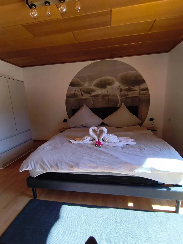 Doppelbett der Ferienwohnung Burgjuwel unter Holzdecke mit Handtuchdekoration