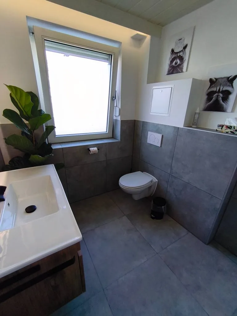 Badezimmer der Ferienwohnung Burgjuwel mit Waschbecken und WC in grauen Fliesen