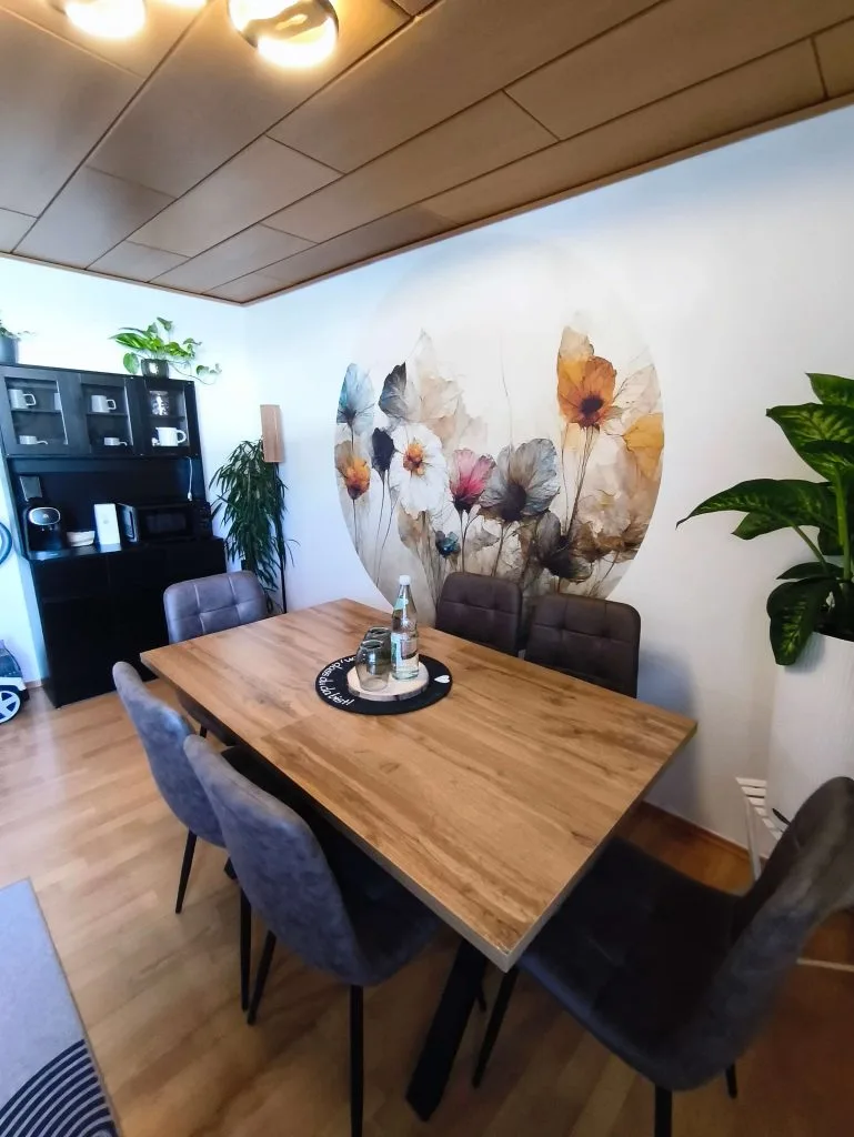 Essbereich der Ferienwohnung Burgjuwel mit floralem Wandbild und Regal