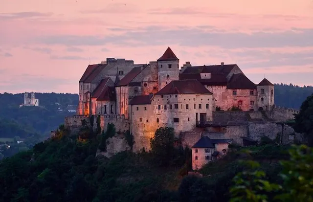 Burg Burghausen im Abendlicht über den bewaldeten Hängen