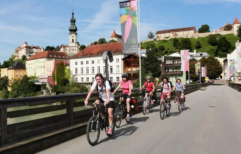 Radfahrergruppe auf einer Brücke mit Blick auf Burg und Altstadt von Burghausen