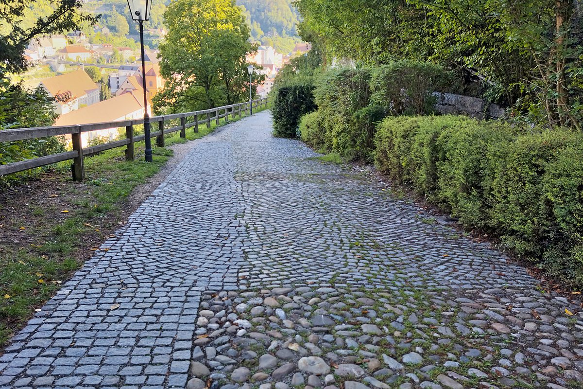 Gepflasterter Fußweg mit Laterne und Hecke hinunter in die Burghauser Altstadt