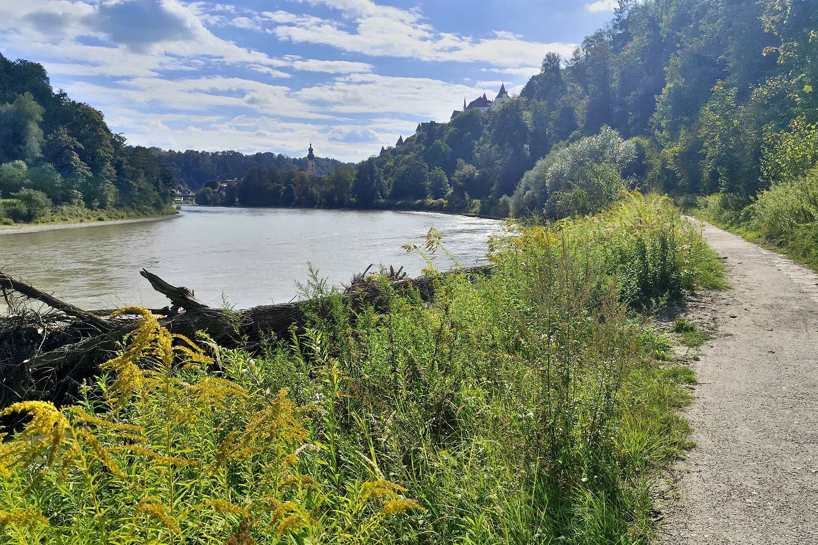 Geschotterter Uferweg an der Salzach, im Hintergrund die Burganlage von Burghausen auf dem Höhenrücken